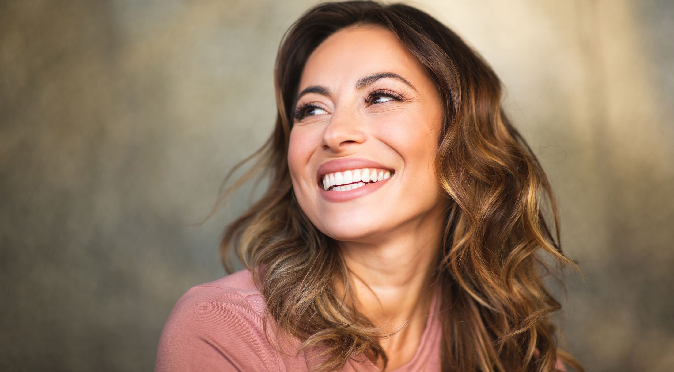 Smiling woman with wavy hair looking sideways.